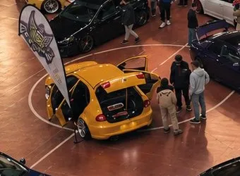 Coche amarillo con las puertas abiertas y equipo de sonido en el maletero